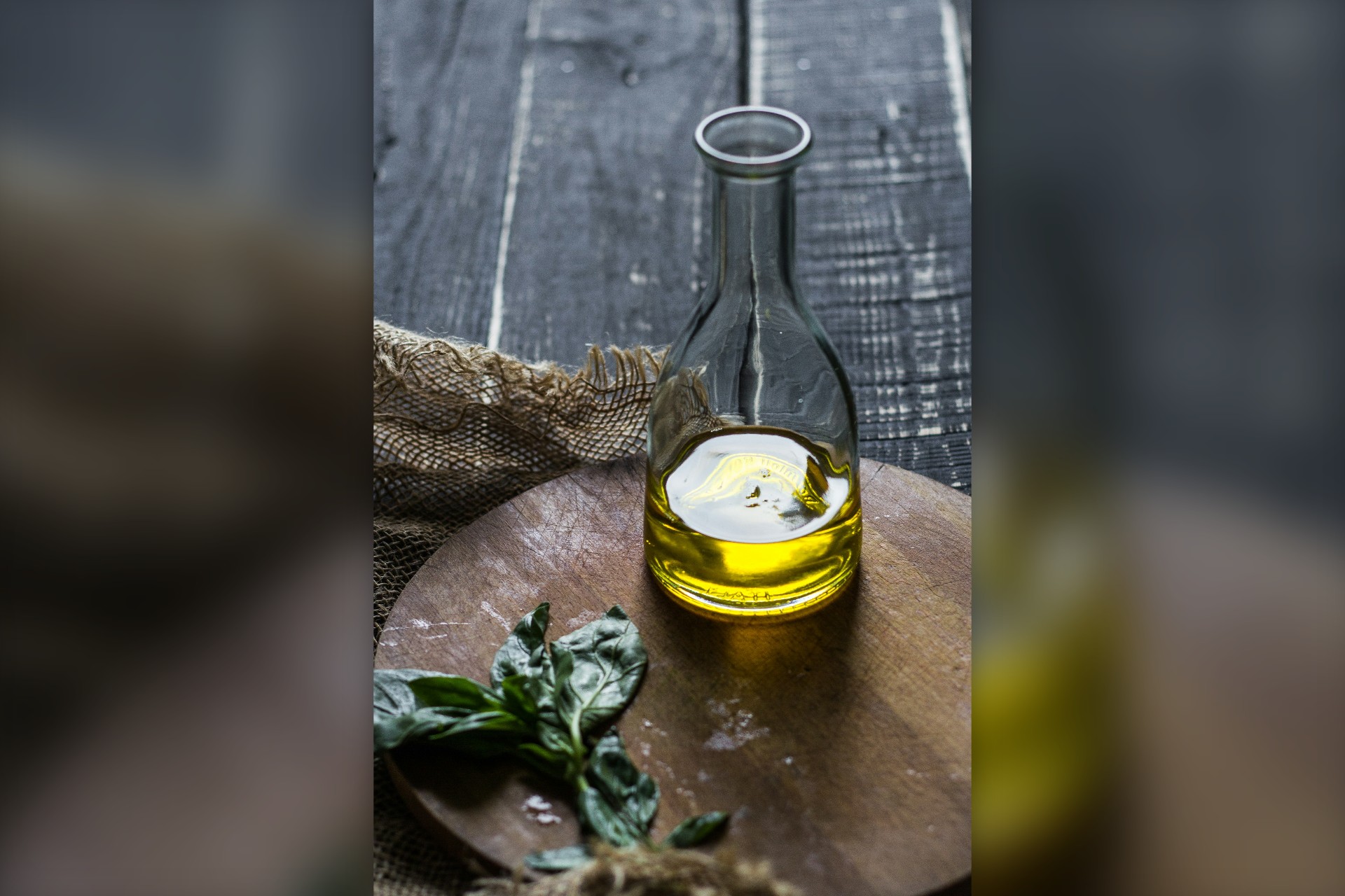 Γυάλινο μπουκάλι με ελαιόλαδο σε ξύλινο τραπέζι