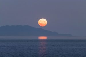 Πανσέληνος που ανατέλλει πάνω από τη θάλασσα